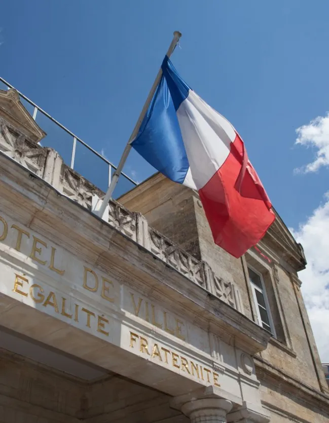 Drapeau français de pavoisement sur la façade d'une mairie.