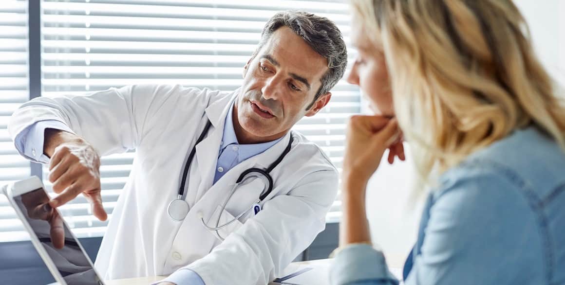 Le médecin montre sa tablette à une patiente.